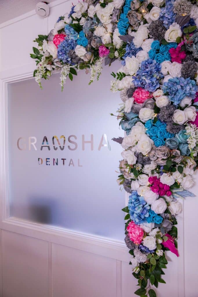 Floral arch around glass door with Gransha Dental logo